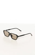 Angled view of black hexagonal-square frame sunglasses with olive tinted lenses and OTRA logo on arms