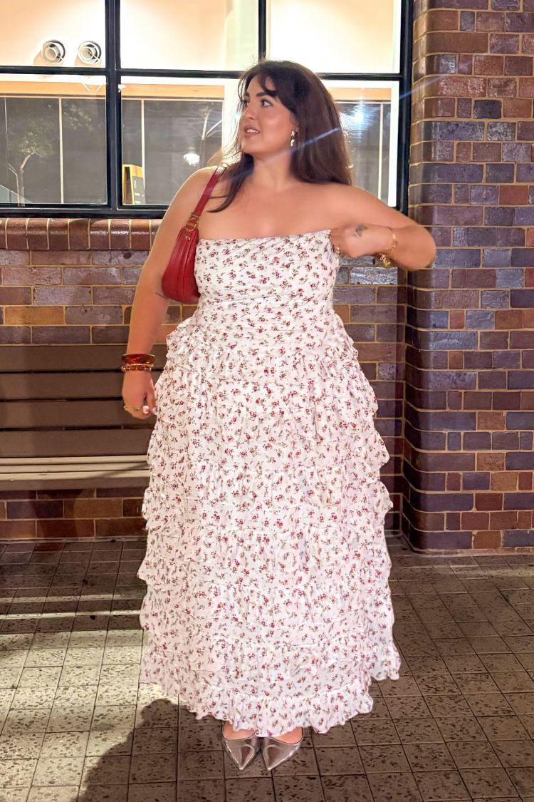 Full length white maxi skirt featuring a small red floral print and multiple tiers of flowing ruffles
