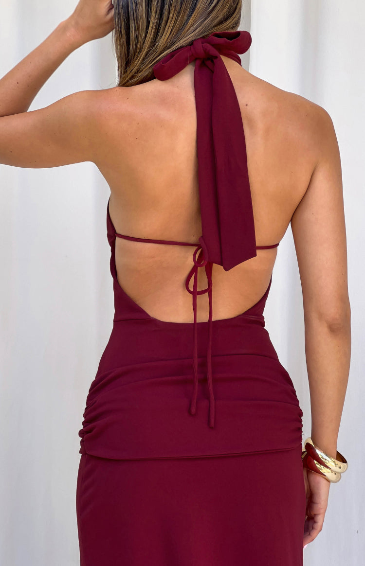 Rear view of a burgundy jersey halter neck formal dress with a tie-back, low scoop back, and ruched skirt