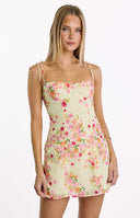 A sweet yellow mini dress with a vibrant pink and orange floral bloom print- featuring a structured bust and dainty tie-shoulder straps- ideal for a garden party or summer event.