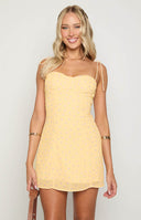 blonde model wearing baby yellow mini dress with purple flower details with bust cup detail and tie straps