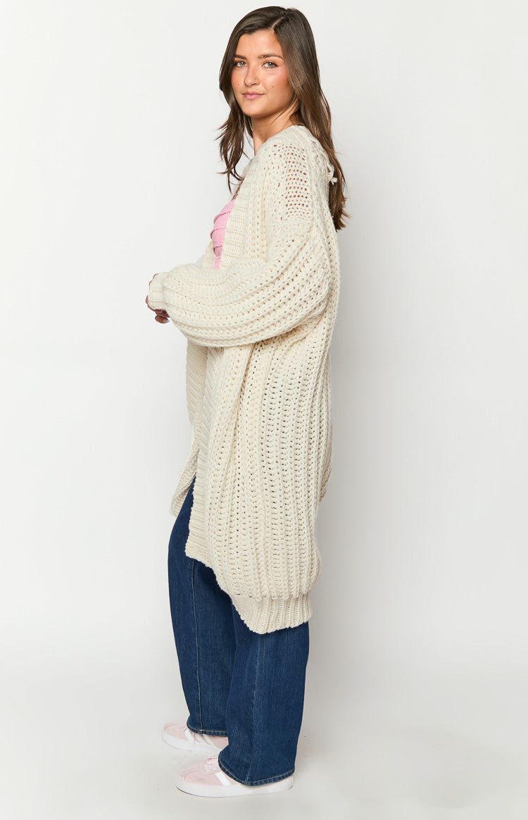 Side view of a cream chunky knit cardigan showing the oversized fit and long balloon sleeves