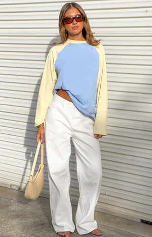 Front view of a blue and yellow contrast raglan sleeve top with a relaxed fit and slightly cropped front