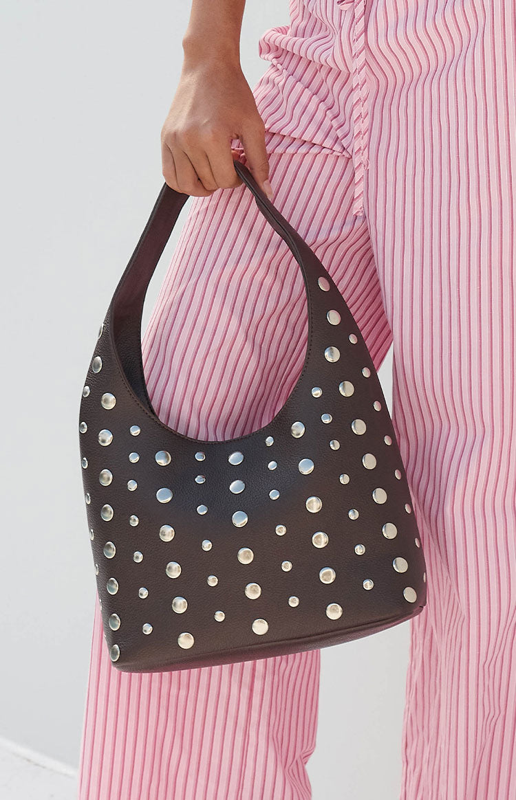 A dark brown handbag with a curved silhouette and all-over silver studs in various sizes.