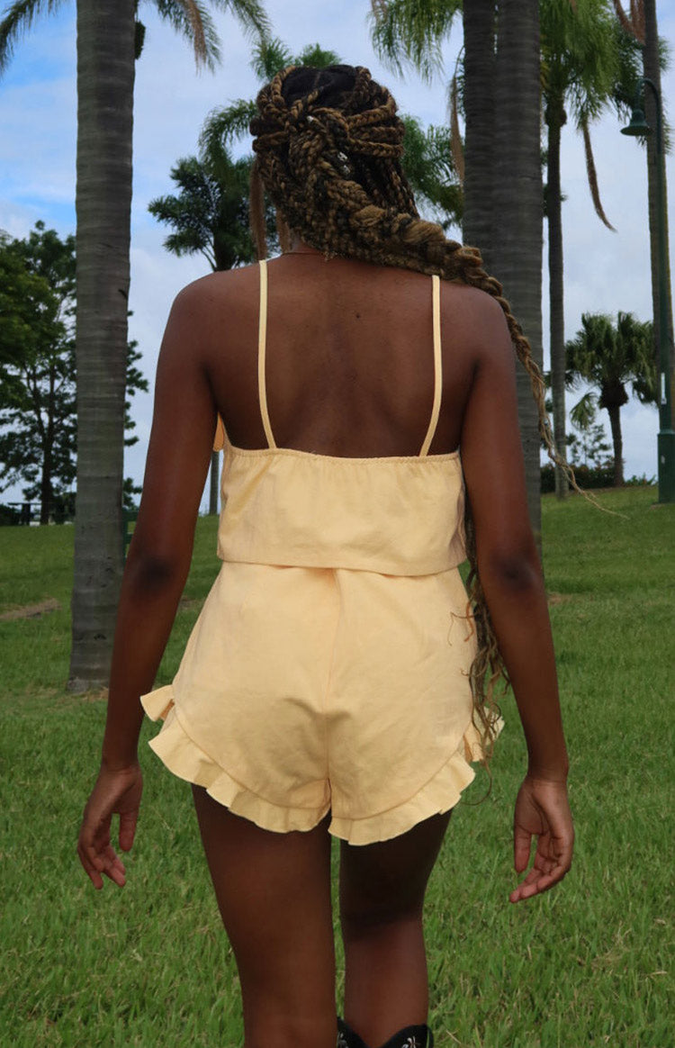 Rear view of a petal yellow crop top with thin spaghetti straps and a gathered elasticated back
