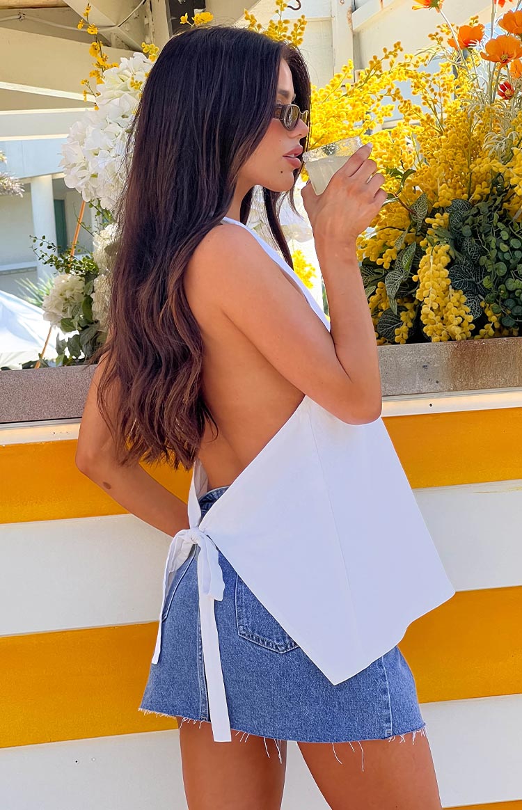 Side view of the white linen blend top showing the open back and waist tie detail