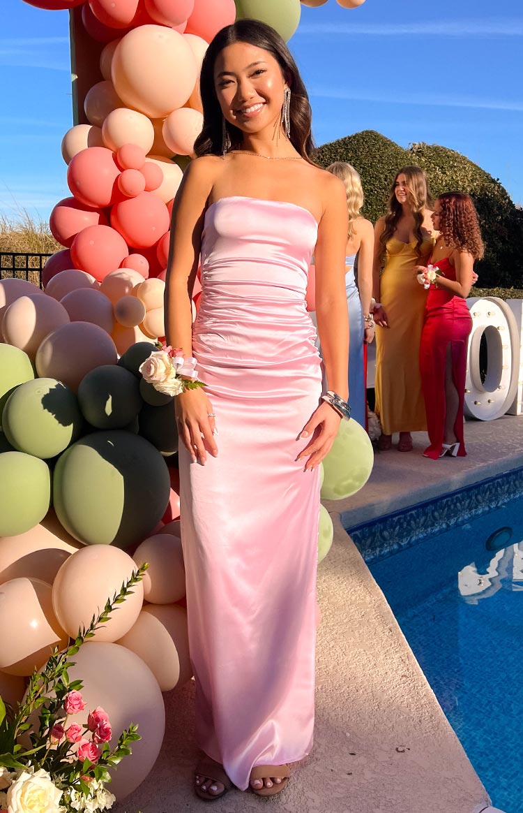 Full length view of a light pink satin strapless maxi dress with a ruched bodice and a flowing skirt