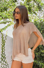 Side view of a light brown metallic knit poncho with an off-shoulder neckline and wide open sleeve
