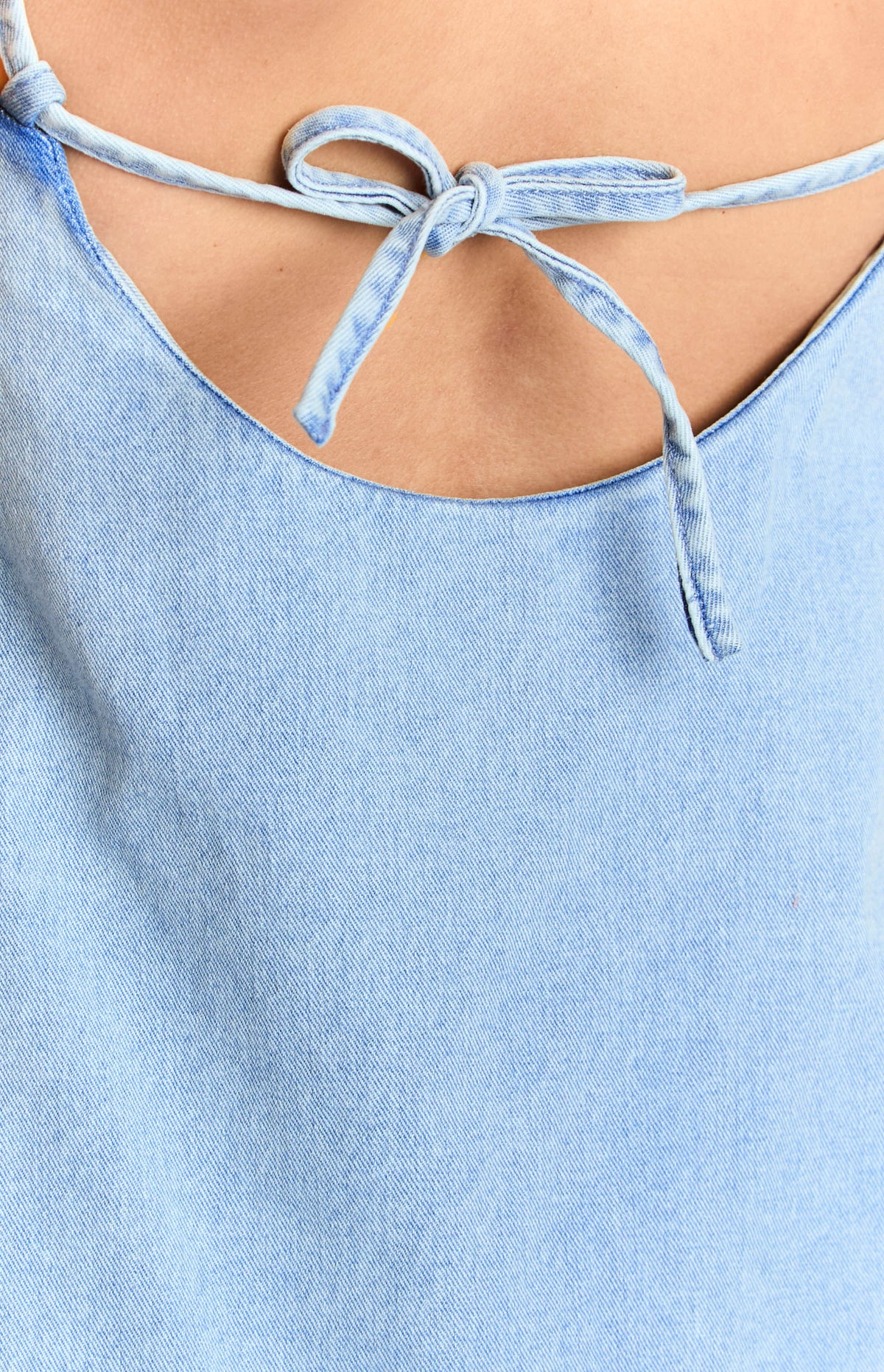 Close-up of the tied bow straps at the back of the mid wash denim dress