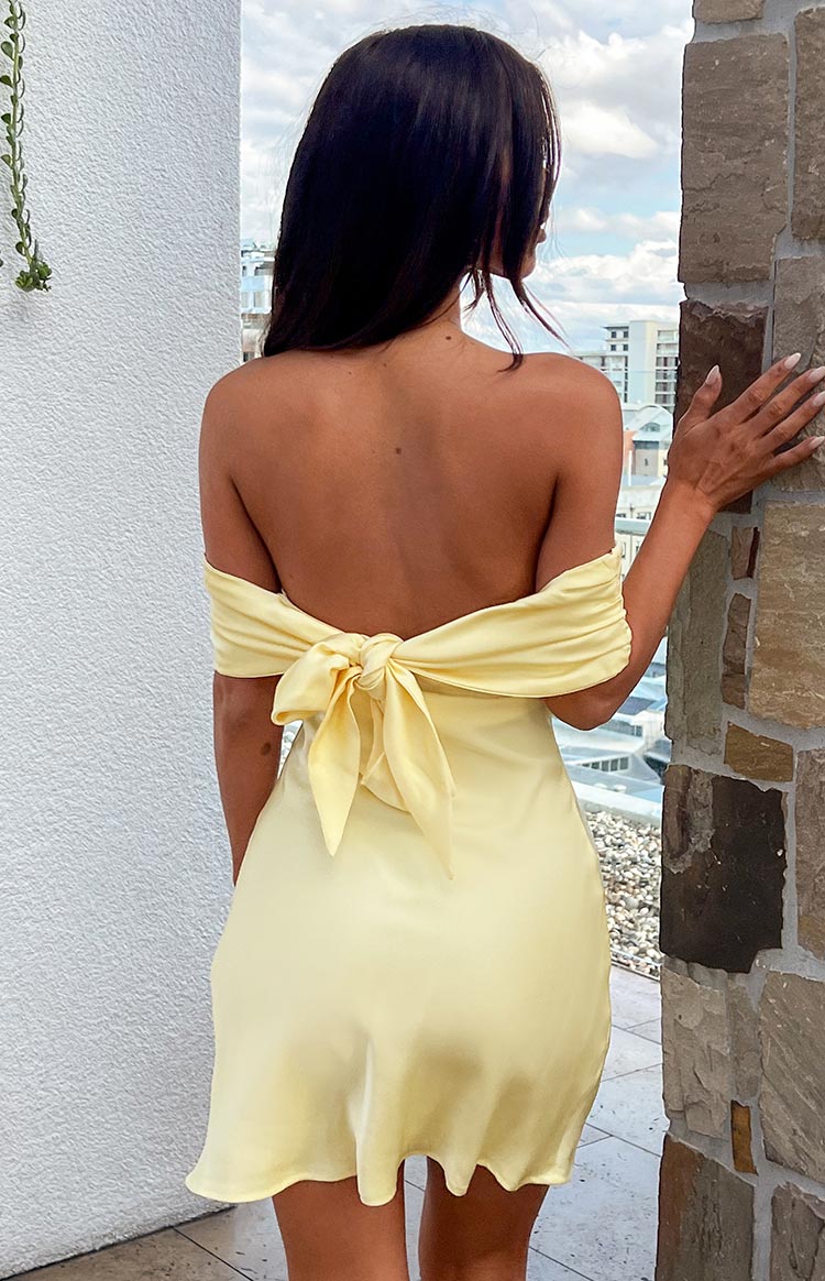 Beginning Boutique Primrose Yellow Satin Off the Shoulder Mini Dress primrose yellow satin off-the-shoulder mini dress with a large tie-back bow and open back