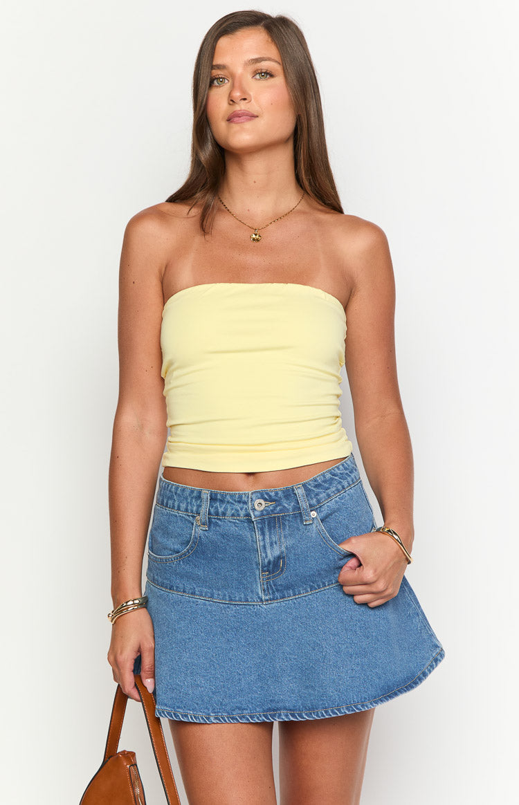 Front view of a mid wash denim mini skirt with a fitted top panel and flared A-line hem