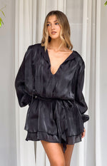 Black satin mini dress with a deep V-neck, long billowy sleeves, tie waist, and tiered ruffle skirt