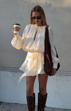 Model in a beautiful pearl satin mini dress with long bishop sleeves a romantic look for a special occasion or date night