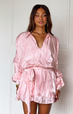 Front view of a pink crinkled satin mini dress featuring a deep V-neck, long cuffed sleeves, and a self-tie waist