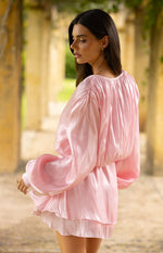Side view of a pink satin mini dress showing the gathered back neckline, blouson bodice, and voluminous long sleeves