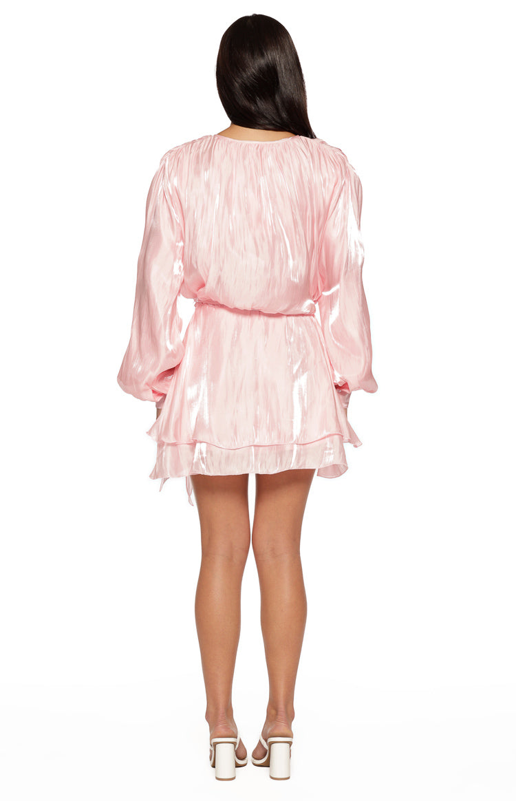 Rear view of a pink crinkled satin long sleeve mini dress with a tie waist and tiered ruffled skirt