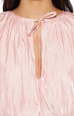 Close-up of the gathered neckline with a keyhole opening and self-tie detail on a pink satin mini dress