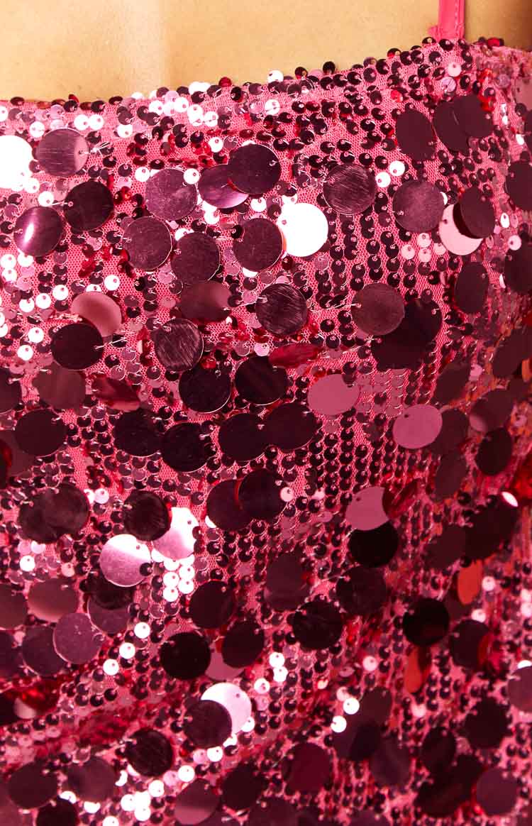 Close-up of the bright pink sequin fabric of the mini dress, showing various sizes of iridescent sequins on a mesh base
