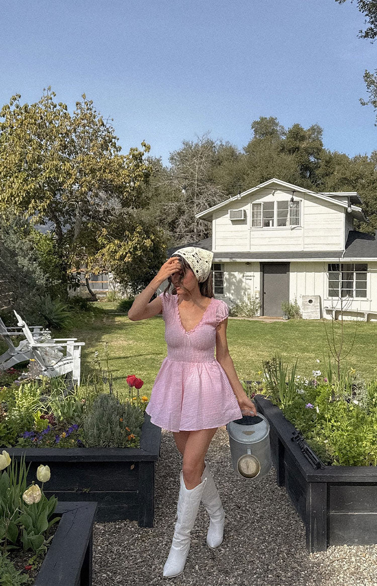 Pink gingham playsuit with V-neck, lace trim, short puff sleeves, smocked bodice, and flared shorts
