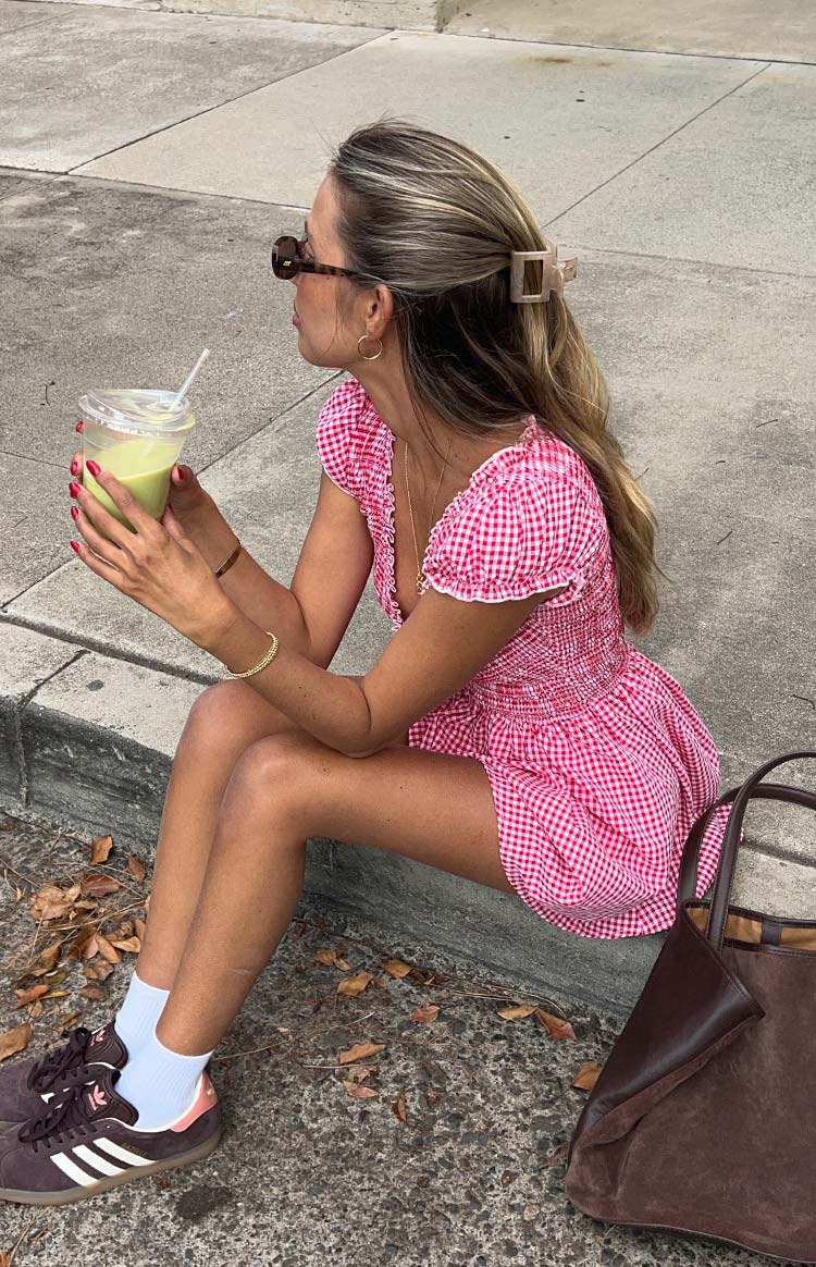 Side view of a red gingham playsuit with a shirred bodice, V-neck, and short puff sleeves