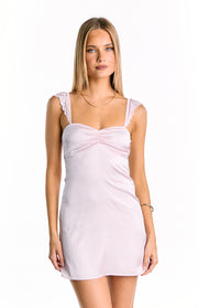 Front view of a light pink mini dress with a ruched sweetheart neckline and lace trim on the shoulder straps