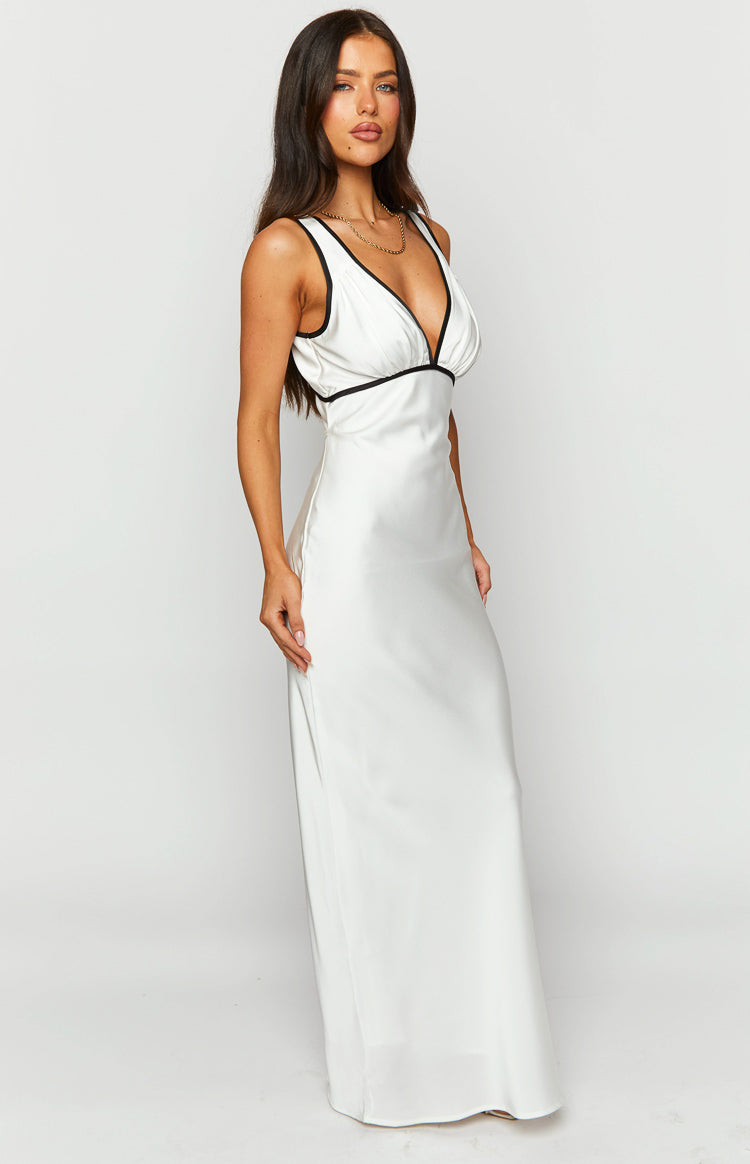 Angled view of a white satin maxi dress with black contrast trim on the deep V-neck and empire waist