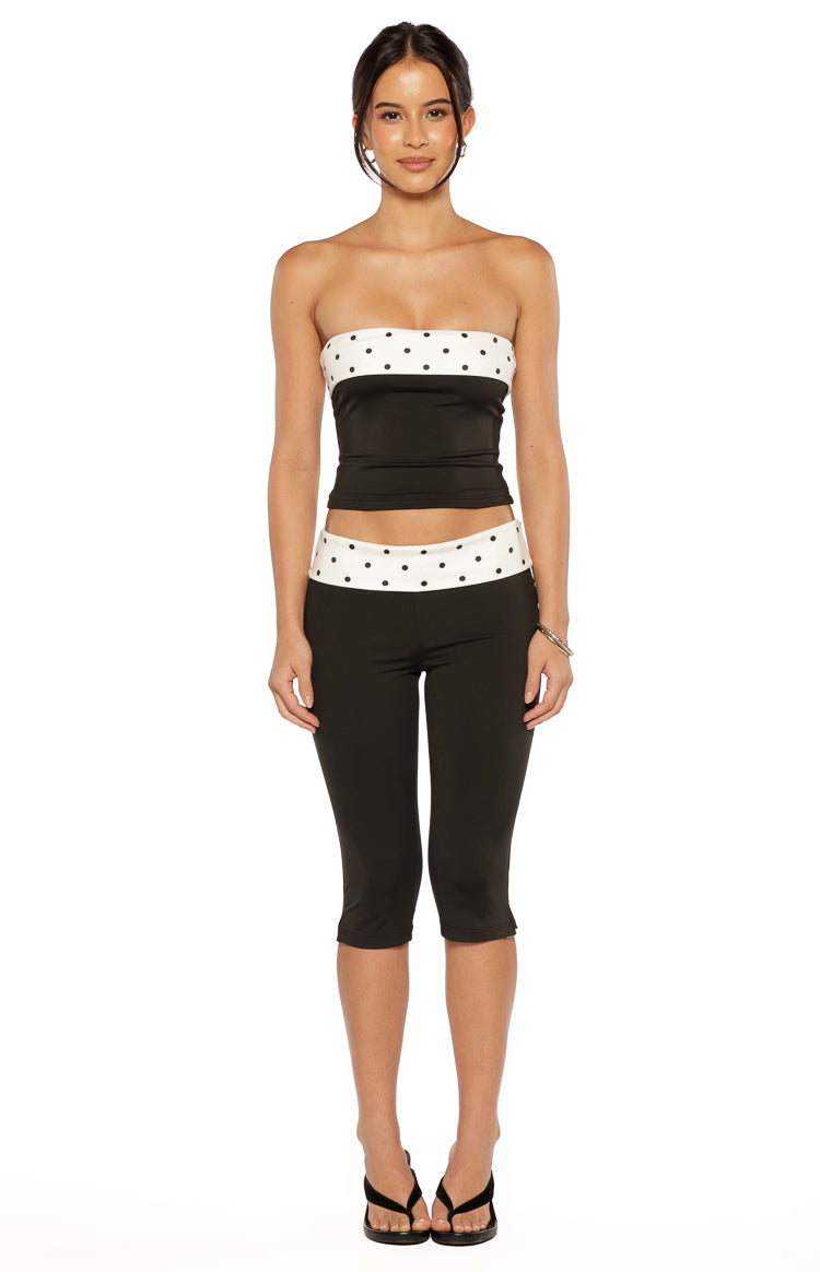 Front view of a black strapless top with a white polka dot band across the bust, fitted silhouette