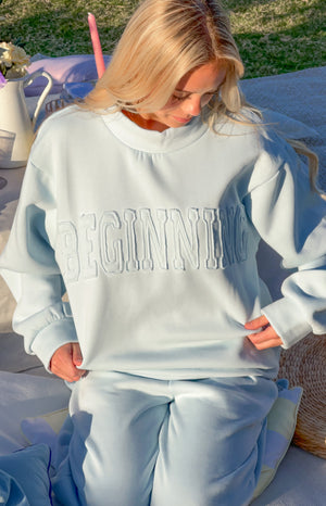Beginning Boutique Remy Blue Applique Mock Neck Sweater light blue mock neck sweater with long sleeves and 'BEGINNING' appliq