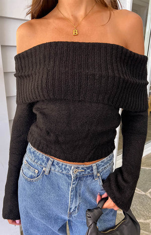Black off-shoulder sweater with a wide ribbed fold-over neckline and long flared sleeves