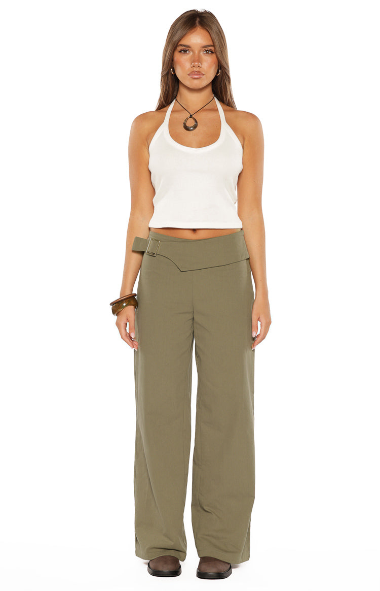 Front view of green straight leg pants with a unique overlapping waistband and a silver buckle detail on the left hip