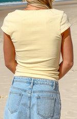 Rear view of a yellow jersey top with light blue polka dots, featuring a boat neck and short sleeves
