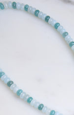 Close-up of the blue beaded necklace showing alternating light blue and teal round beads
