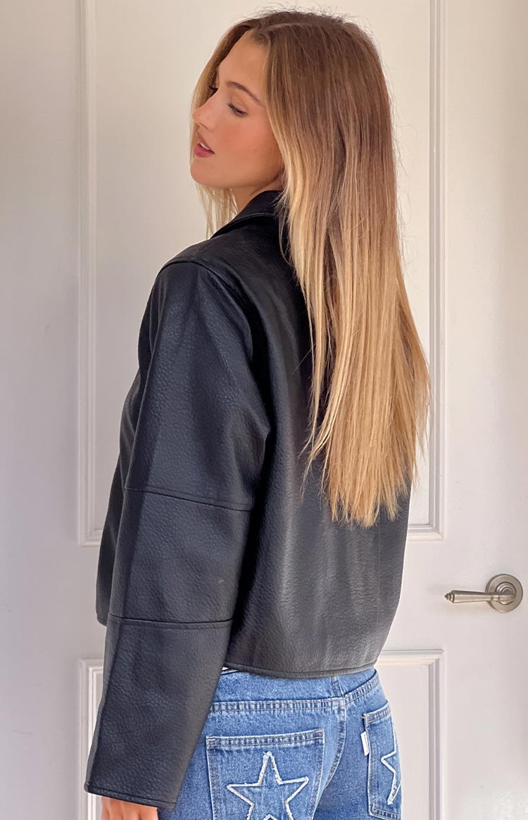 Side view of the black pebbled PU cropped jacket showing the hemline and seamed sleeves