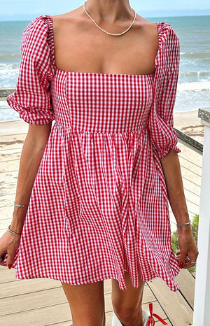 Close-up of the square neckline and puffed sleeves of a red gingham babydoll mini dress