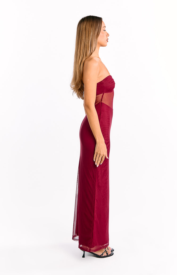 Side view of a wine strapless mesh maxi dress with ruched bodice and sheer mesh side panels