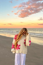 Cream knit sweater with large pink flower pattern, relaxed fit, and long balloon sleeves with ribbed cuffs