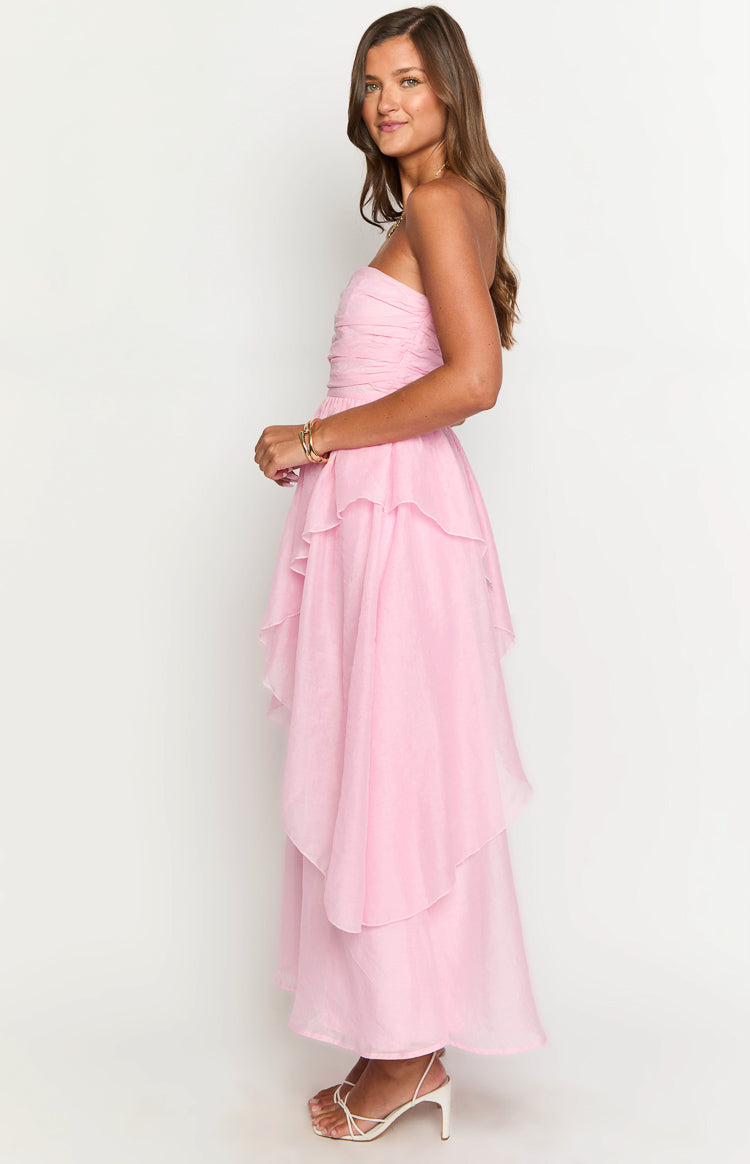 Side view of a pink strapless maxi dress with a ruched bodice and tiered ruffled high-low skirt