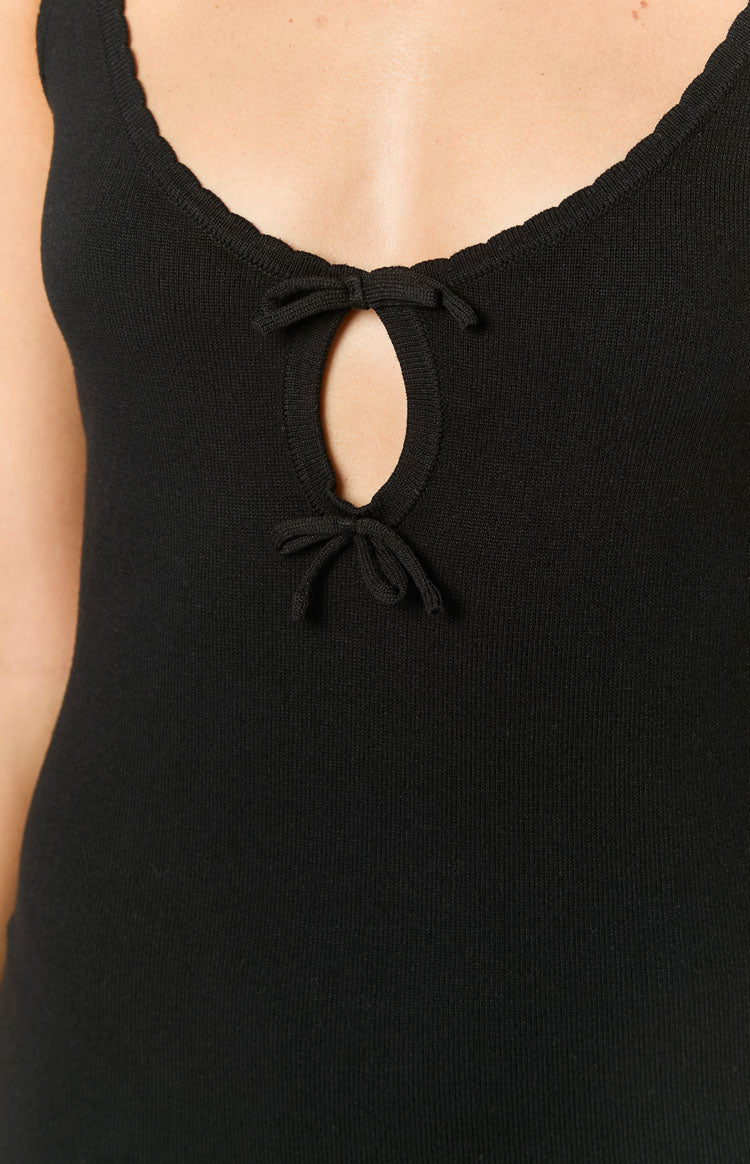 Close-up of the black ribbed knit mini dress with a scalloped neckline and a keyhole cutout featuring bow ties