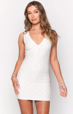 Fitted white mini dress with a textured diamond pattern, V-neckline, and sleeveless design