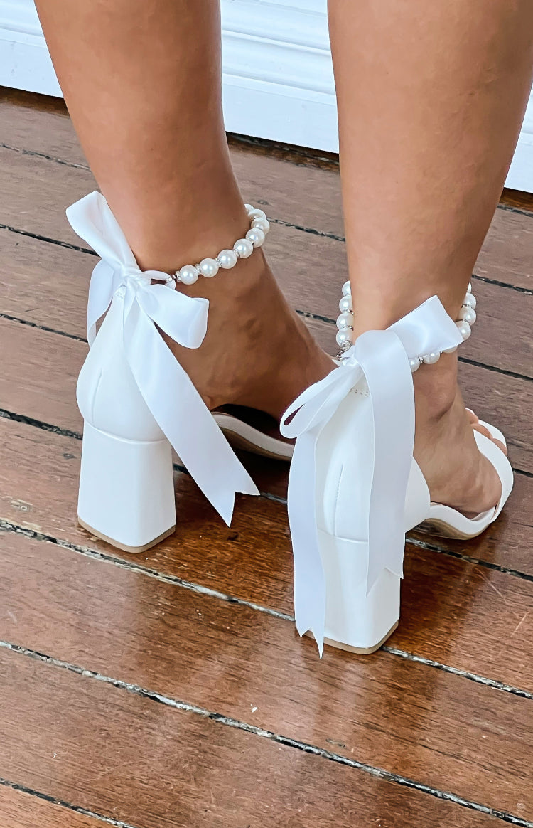 Rear view of white block heels with satin ribbon ties and a pearl ankle strap