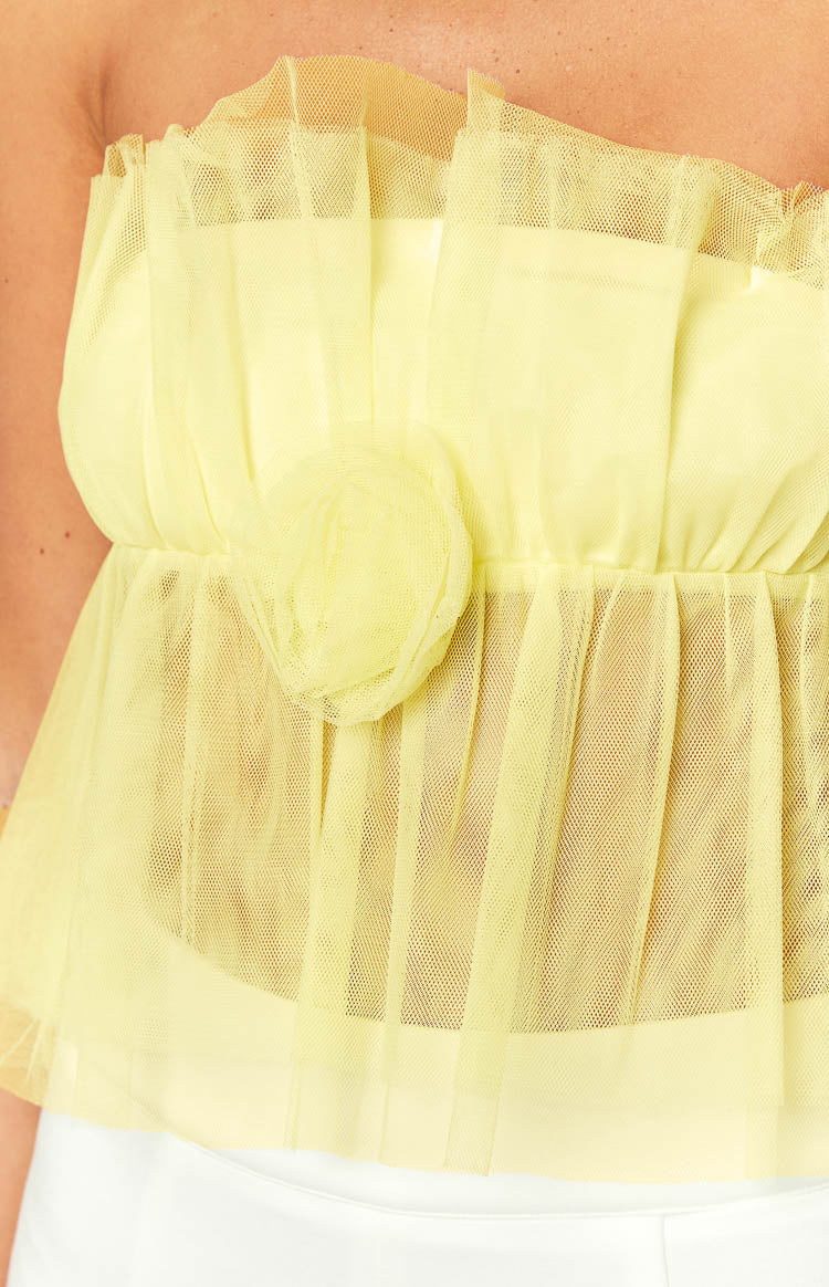 Close-up of the yellow tulle crop top showing the ruffled strapless neckline, gathered waist, and 3D flower detail
