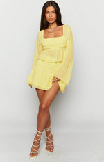 Yellow chiffon long sleeve top featuring a square neckline, shirred bodice, sheer sleeves, and a peplum hem