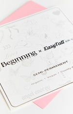 White sheet of semi-permanent tattoos featuring light grey butterflies, cowboy hats, cherubs, and text Organic Vegan