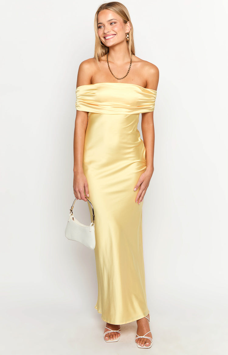 Yellow satin off-the-shoulder maxi dress with a wide draped neckline and a sleek, flowing silhouette