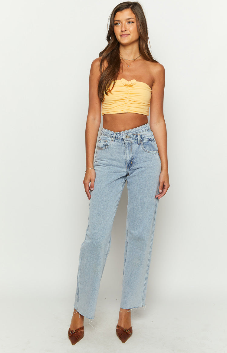 Front view of a yellow strapless ruched crop top with a small bow detail on the bust