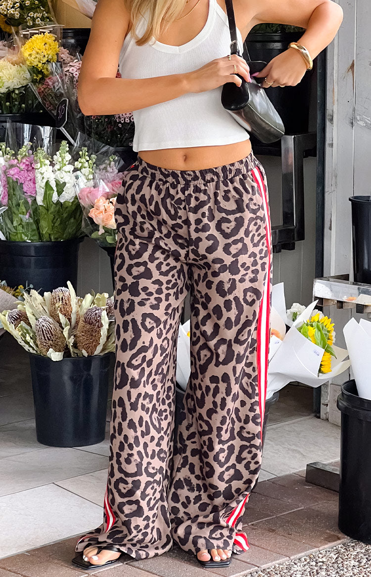 Full length view of the flowy leopard print wide-leg pants with red and white racer stripes