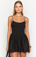 Brunette model wearing a black ini dress with a shirred bust and flared skirt