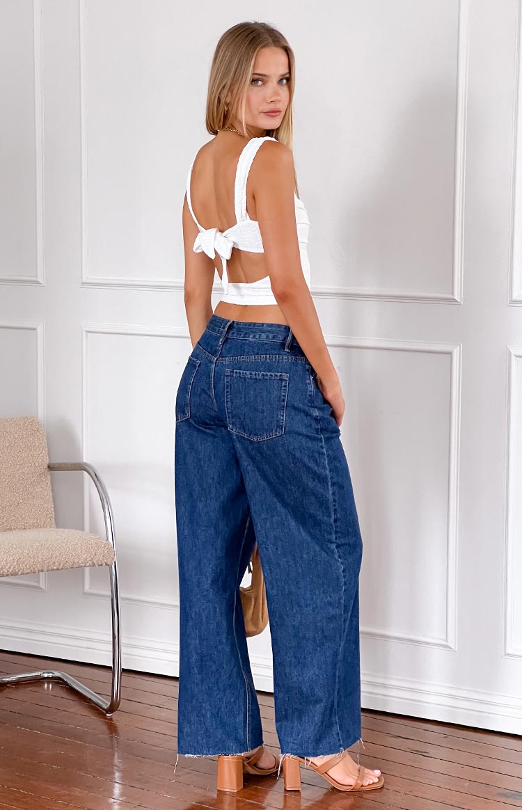 Rear view of dark wash denim wide leg boyfriend jeans with back pockets and a raw hem