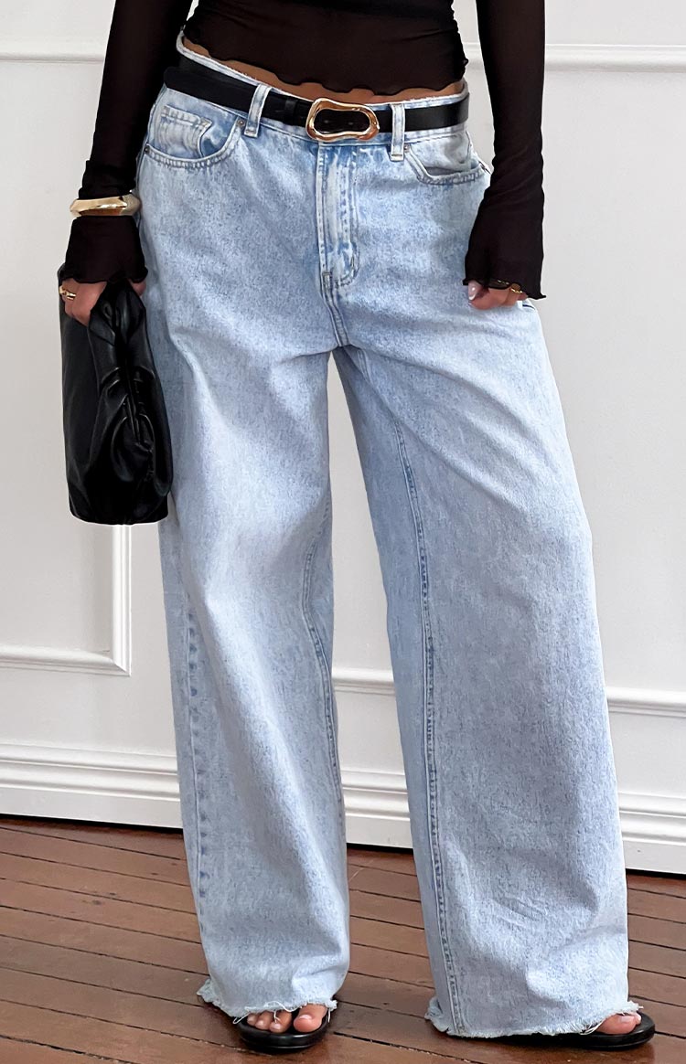 Light wash wide leg boyfriend jeans with a prominent front seam and frayed hem