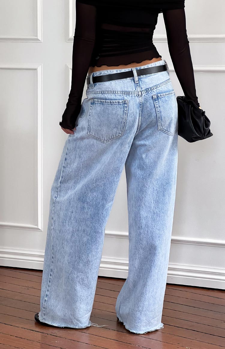 Rear view of light wash wide leg boyfriend jeans showing back pockets and raw hem